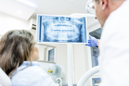 A dentist shows a dental patient an x-ray of their teeth