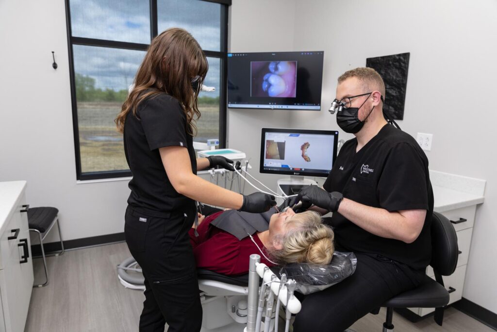 Dentist and dental assistant working on a patient in a dental chair.